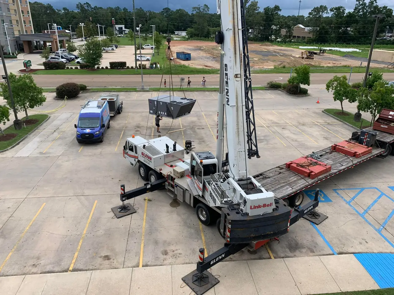 Crane setting a rooftop HVAC unit at a commercial job site