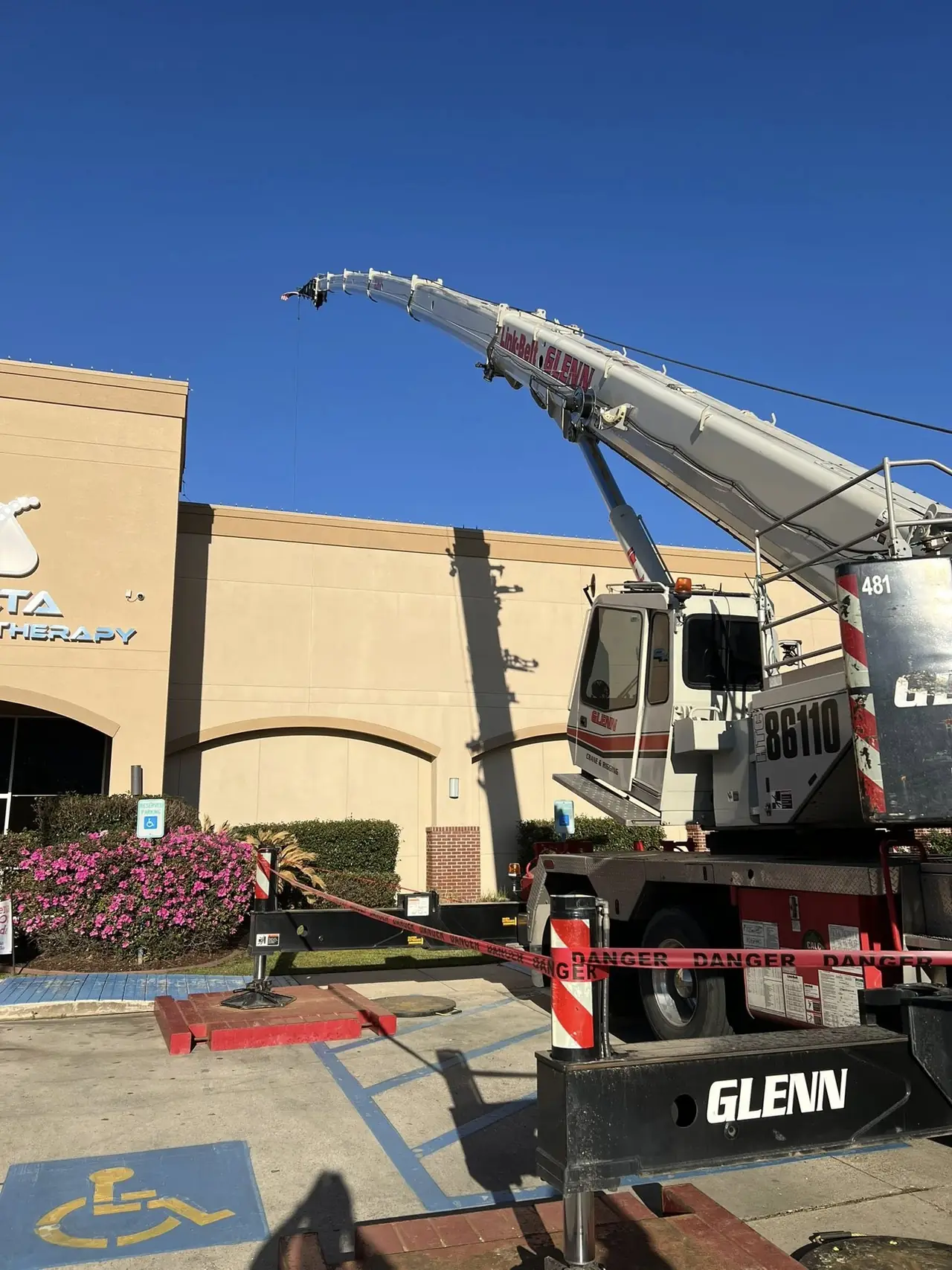 Crane lifting HVAC equipment at a shopping center