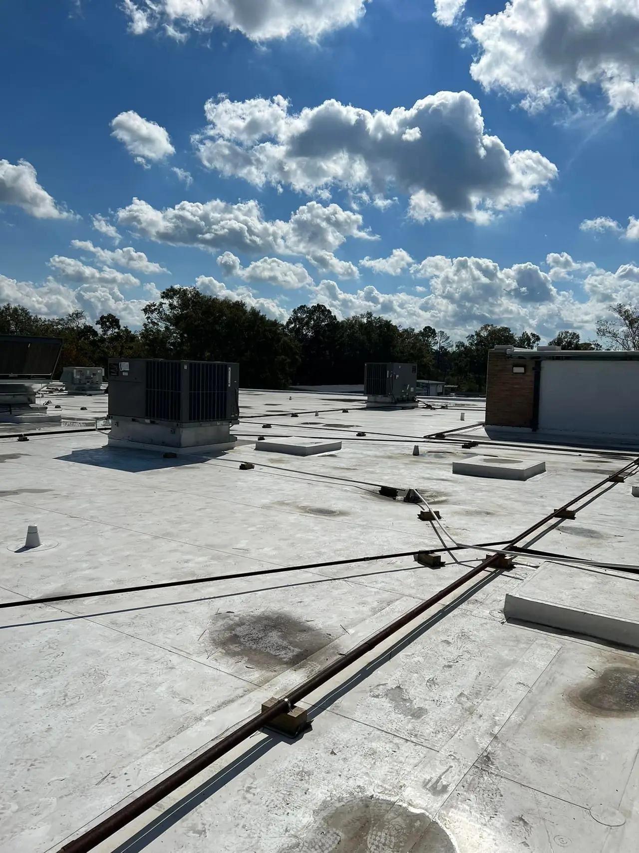 Rooftop units on a flat commercial roof under a blue sky