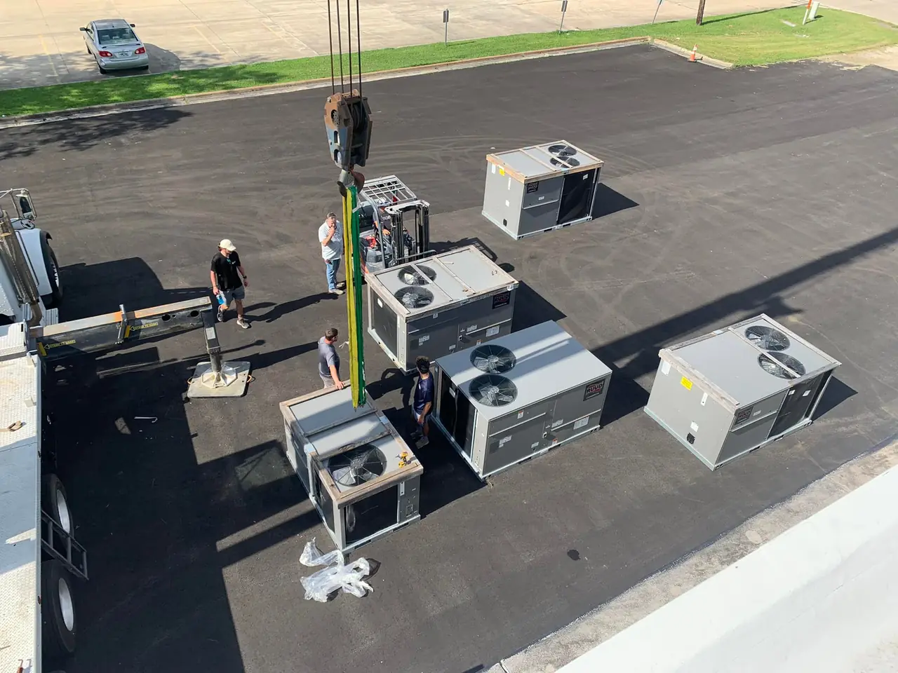 Crew setting new rooftop package units on a commercial roof